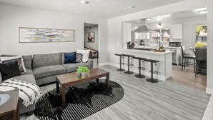 A modern living room with a grey sofa, a wooden coffee table, and a black and white rug.