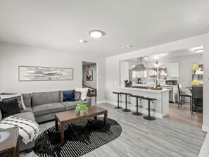 A modern living room with a grey sofa, a wooden coffee table, and a black and white rug.