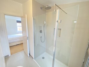 Ein modernes Badezimmer mit einer Glaskabine zur Dusche, einer Toilette und einem Waschbecken.