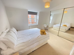 Relax in a spacious bedroom with a large bed, glass desk, and expansive window view.
