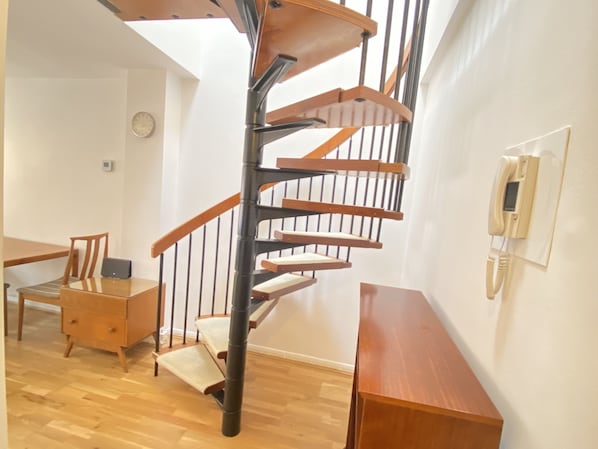 Stunning spiral staircase leads to a cozy dining area with a wooden table and chairs.