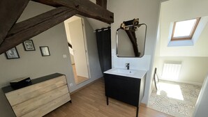 Ein modernes Badezimmer mit einem Holzwaschtisch, einem schwarzen Waschbecken und einem Spiegel. Über dem Waschbecken befindet sich ein Oberlicht und eine Tür zu einem anderen Raum.