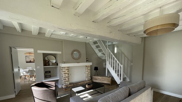 Ein geräumiges Wohnzimmer mit Kamin, Treppe und einer modernen Couch.