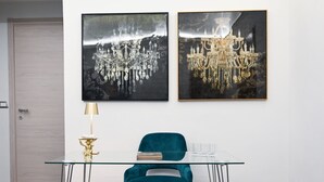 A modern room with a glass desk, teal chair, and two framed artworks depicting chandeliers. - Gikla maison in the heart of Catania (Catania)