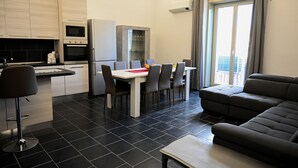 A modern kitchen with a dining area, a sofa, and a view of the city. - Gikla maison in the heart of Catania (Catania)