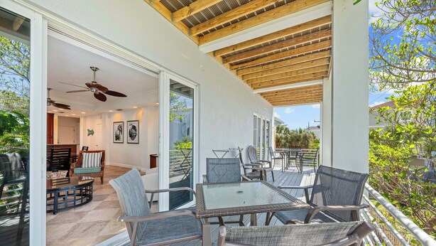 An outdoor patio with a table and chairs, a ceiling fan, and a view of the surrounding area.