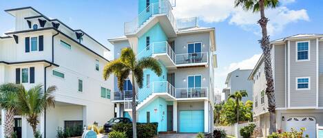 A multi-story residential building with a central staircase, a garage, and a well-maintained lawn.