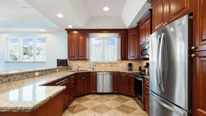 A kitchen with wooden cabinets, a stainless steel refrigerator, and a dishwasher.