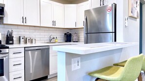A modern kitchen with white cabinets, stainless steel appliances, a built-in island, and a coffee maker.