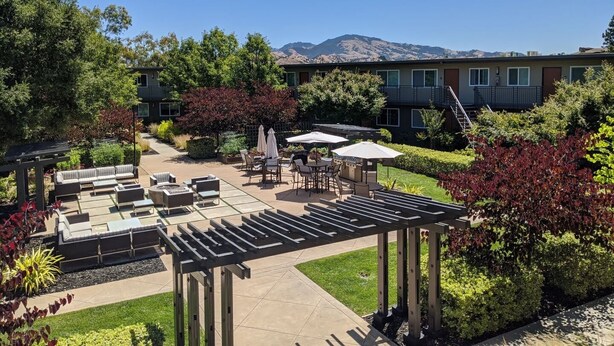 A courtyard with outdoor seating, a pergola, and a view of mountains.