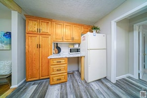 Una cocina compacta con armarios de madera, un microondas y un refrigerador.