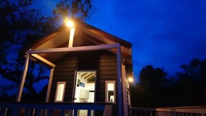 A small, single-story cabin with a porch and a visible interior including a kitchen area. - Tiny House Garden - Praia Grande - SC (Praia Grande)
