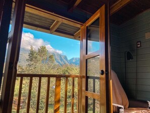 Een houten chalet met balkon en uitzicht op een bergachtig landschap.