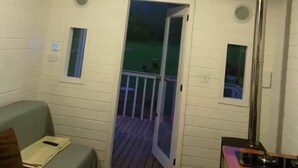A cozy room with a wooden ceiling, a built-in bench, a small table, and a door leading to an outdoor deck. - Tiny House Garden - Praia Grande - SC (Praia Grande)