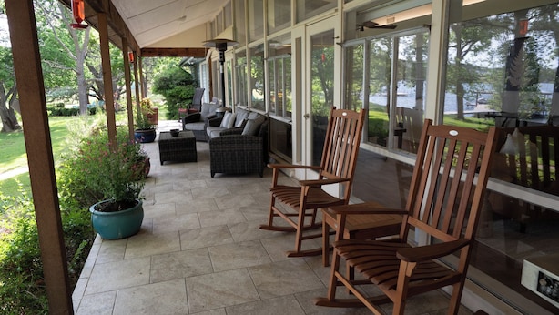 A covered patio with wicker furniture, potted plants, and a view of a lake. - Inks Lake Open Water and Pet friendly home (Burnet)