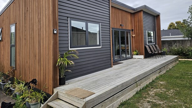 Una casa moderna de dos pisos con fachada de madera y techo gris.