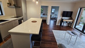 Una cocina moderna con una isla central, un comedor y una sala de estar con televisor y asientos.