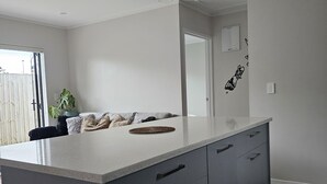 Una cocina moderna con una isla grande, muebles grises e iluminación colgante.
