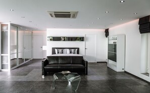 A modern bedroom with a bed, a glass coffee table, a wardrobe, and a sliding glass door.