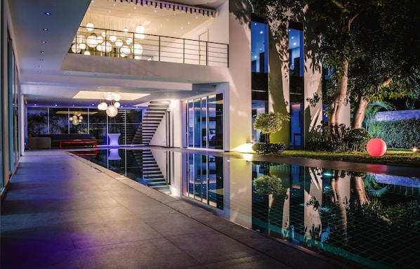 A modern building with a reflective pool, a staircase, and a seating area with a sofa and a coffee table.