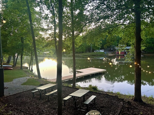A lakeside picnic area with wooden benches and a dock extending into the water.