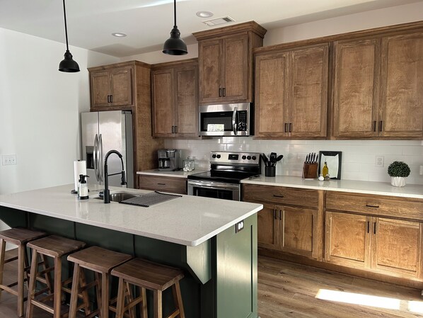 Une cuisine moderne avec des meubles en bois, des appareils en acier inoxydable et un grand îlot central doté de tabourets.