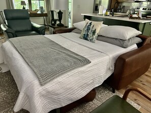 Relax in comfort with a large bed, cozy seating area, and kitchenette, perfect for a convenient stay.