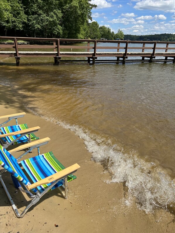 A beach with a wooden pier and striped beach chairs.