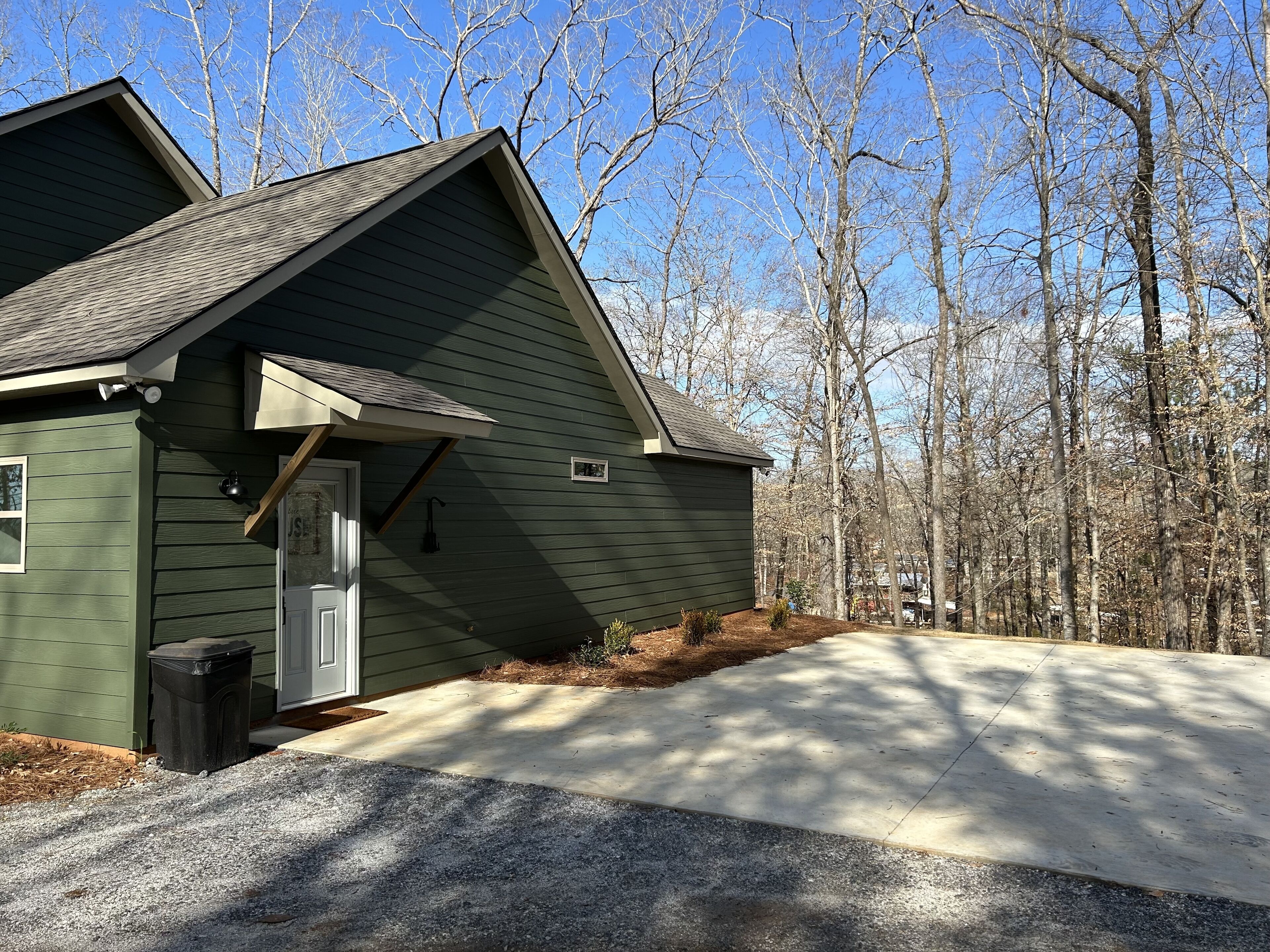 A green house with a sloped roof, a front door, and a small attached garage.