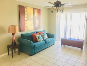 Relax in this stylish living room with a sofa, side table, and lamp, surrounded by colorful artwork and additional seating.