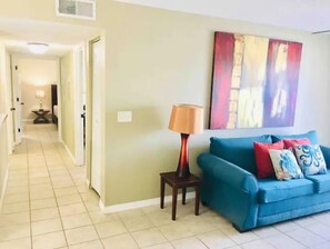 Relax in this inviting living area with a sofa, floor lamp, and abstract art.