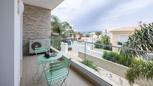 Un balcón con mesa y sillas, vista del paisaje urbano y una pared de ladrillo.