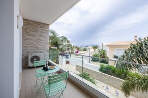 A balcony with a table and chairs, a view of the cityscape, and a brick wall. - CoolHouses Algarve Lagos | Amor à Vida T3 (Lagos)