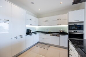 A modern kitchen with white cabinetry, a black countertop, and stainless steel appliances. - CoolHouses Algarve Lagos | Amor à Vida T3 (Lagos)