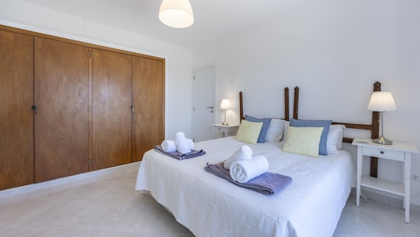 Una camera d'albergo con un letto, due comodini, un armadio e una lampada a soffitto.