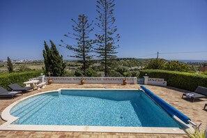 Ein Schwimmbecken mit Blick auf das Meer und eine Stadtlandschaft im Hintergrund.