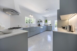 A modern kitchen with a gas stove, a large island, and a built-in oven. - CoolHouses Algarve Lagos | Casa Fernanda (Lagos)