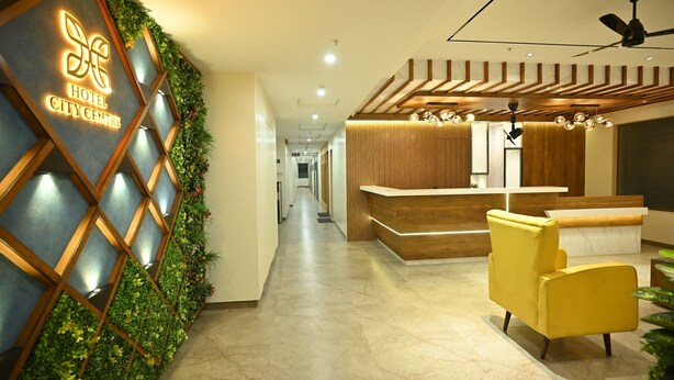 A hotel reception area with a modern design, including a reception desk, a yellow armchair, and a wall-mounted sign. - Hotel City Centre Latur (Latur)