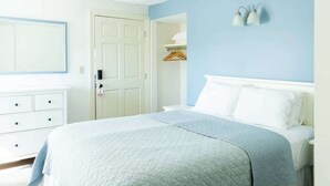 A bedroom with a bed, a dresser, a door, and a wall-mounted light fixture. - #2 | Comfy Room w/ Queen-bed (Middletown)
