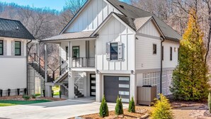 A modern two-story house with a covered porch, a garage, and a landscaped front yard. - Luxury Waterfront Getaway (Cullowhee)