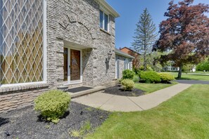 A stone house with a front door, a small front yard with a pathway, and a tree with red leaves.