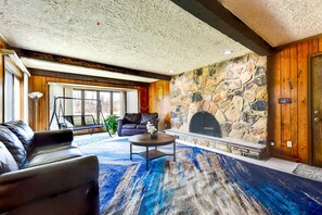 A living room with a stone fireplace, leather sofa, and a large window.