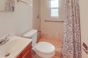 Un baño con inodoro, lavamanos y zona de ducha.