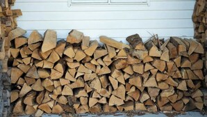 A house with a window and a stack of firewood against the wall.