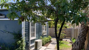 A residential backyard with a house, a tree, a fence, and an air conditioning unit. - Cheerful Cottage Close to the Beach! (Lake Worth)