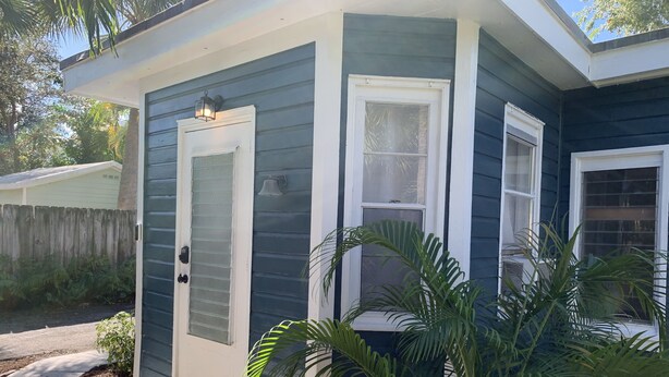 A house with a front door, a window, and a small porch area with plants. - Cheerful Cottage Close to the Beach! (Lake Worth)