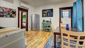 Una cocina moderna con refrigerador, cafetera y lavaplatos. Hay una mesa de comedor con sillas y un jarrón azul.