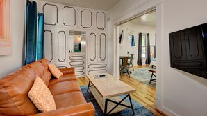 Una sala de estar con un sofá de cuero marrón, una mesa de centro de madera y un mueble blanco con detalles decorativos.