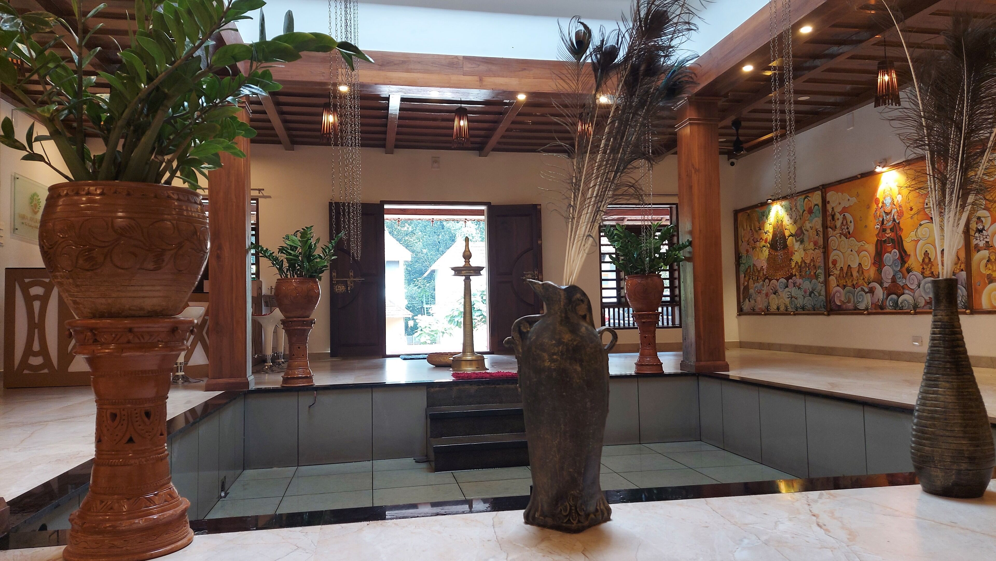 A lobby with large vases, a statue, and a mural.