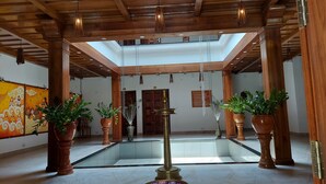 A spacious lobby with a high ceiling, wooden beams, and a central water feature.